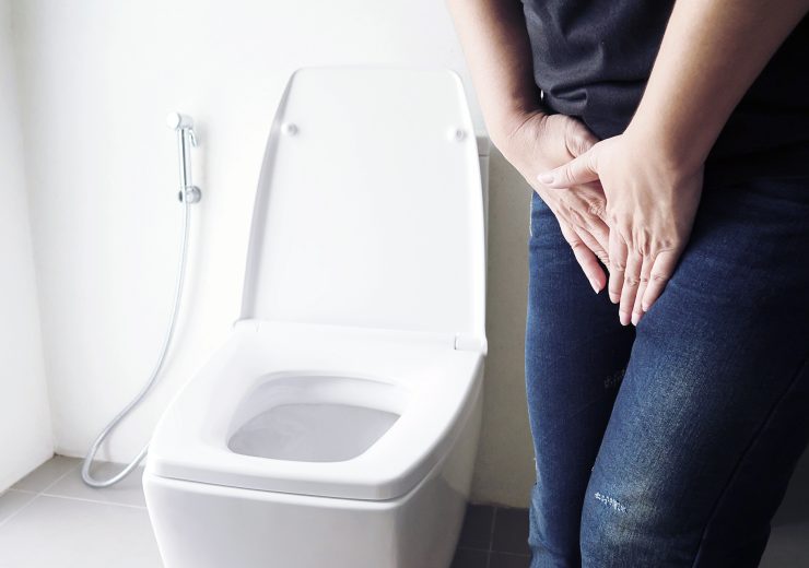 Woman holding hand near toilet bowl - health problem concept