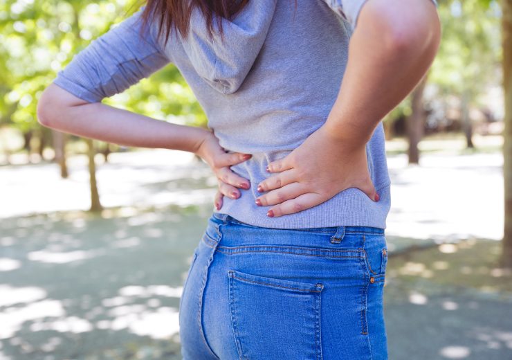 Closeup of young woman touching waist in park