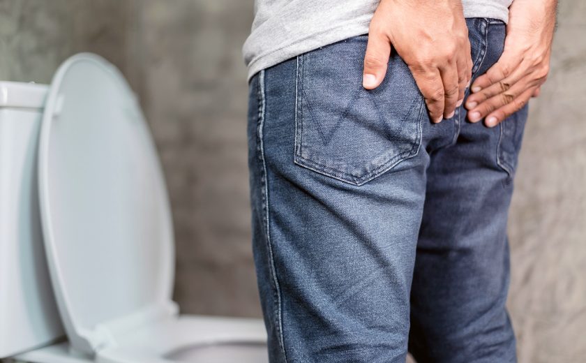 Man standing and holding on the back side in the toilet. Concept