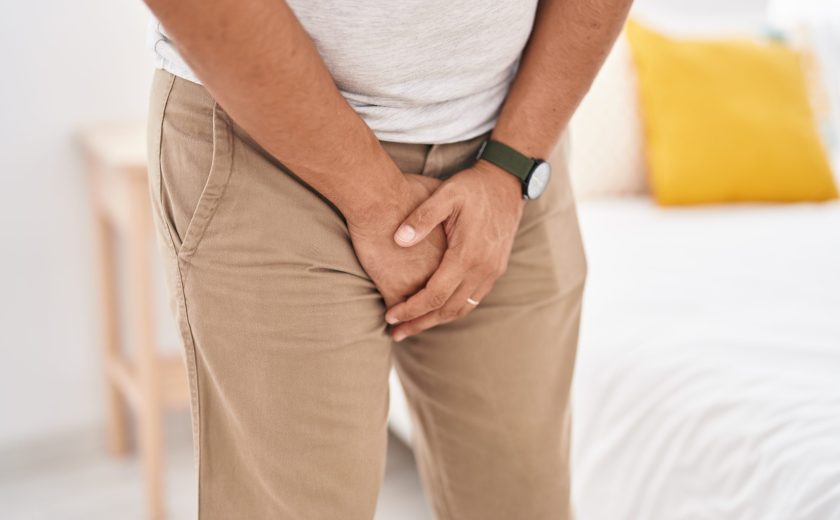 Young latin man covering his genitals with hands at bedroom